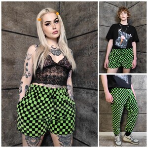 May include: A selection of clothing with a green and black chequered design. The items include shorts and trousers. One person is wearing a black lace top and chequered shorts. Another is wearing a black t-shirt and chequered shorts. A third is wearing chequered trousers.