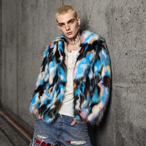 Op de afbeelding: Een kleurrijke imitatiebontjas met blauwe, zwarte, bruine, roze en witte tinten. De jas heeft een kraag en lange mouwen. Het model draagt een wit overhemd en een gescheurde blauwe jeans.