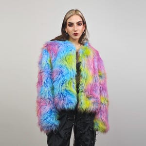 Può includere: Giacca in finta pelliccia dai colori vivaci, con un motivo tie-dye blu, rosa e giallo. La giacca aperta ha una consistenza soffice. Questo capo di tendenza aggiunge un tocco di colore audace a qualsiasi outfit. Un capo di moda divertente e accattivante.