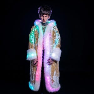 May include: A gold sequined coat with a white faux fur trim and hood. The coat features color-changing LED lights along the trim and cuffs, creating a vibrant, illuminated effect. The coat is a unique fashion statement.