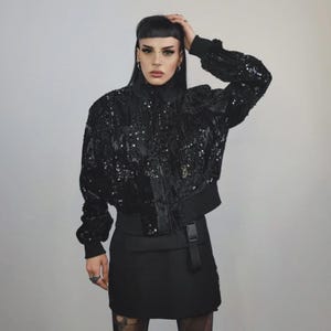 This embellished varsity jacket is the definition of dark glamour. The gloss glitter sequins create an unforgettable shiny effect. Styled as an oversized cropped blazer or a short bomber, this unisex embellished piece is ready for the club or a festive gathering. A durable, show-stopping coat for your boldest maximalist ensembles, providing the essential sparkle for any disco look.