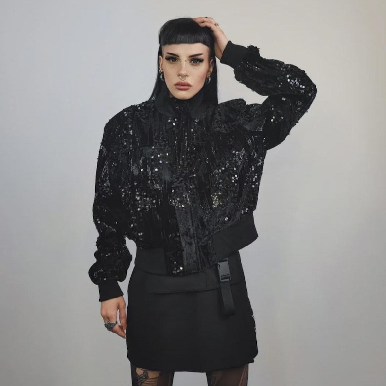 This embellished varsity jacket is the definition of dark glamour. The gloss glitter sequins create an unforgettable shiny effect. Styled as an oversized cropped blazer or a short bomber, this unisex embellished piece is ready for the club or a festive gathering. A durable, show-stopping coat for your boldest maximalist ensembles, providing the essential sparkle for any disco look.