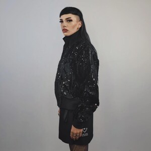 This embellished varsity jacket is the definition of dark glamour. The gloss glitter sequins create an unforgettable shiny effect. Styled as an oversized cropped blazer or a short bomber, this unisex embellished piece is ready for the club or a festive gathering. A durable, show-stopping coat for your boldest maximalist ensembles, providing the essential sparkle for any disco look.