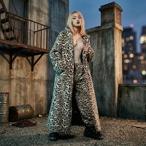May include: A person wears a long leopard-print coat and matching trousers on a rooftop. The coat is open, showing a beige top. The outfit is completed with black platform boots. The background features a cityscape and a metal fire escape.