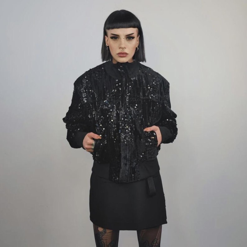 This embellished varsity jacket is the definition of dark glamour. The gloss glitter sequins create an unforgettable shiny effect. Styled as an oversized cropped blazer or a short bomber, this unisex embellished piece is ready for the club or a festive gathering. A durable, show-stopping coat for your boldest maximalist ensembles, providing the essential sparkle for any disco look.
