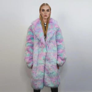 May include: A long faux fur coat in pastel shades of pink, blue, and purple. The coat features a wide collar and long sleeves. The knee-length coat is made from a soft, fluffy material.