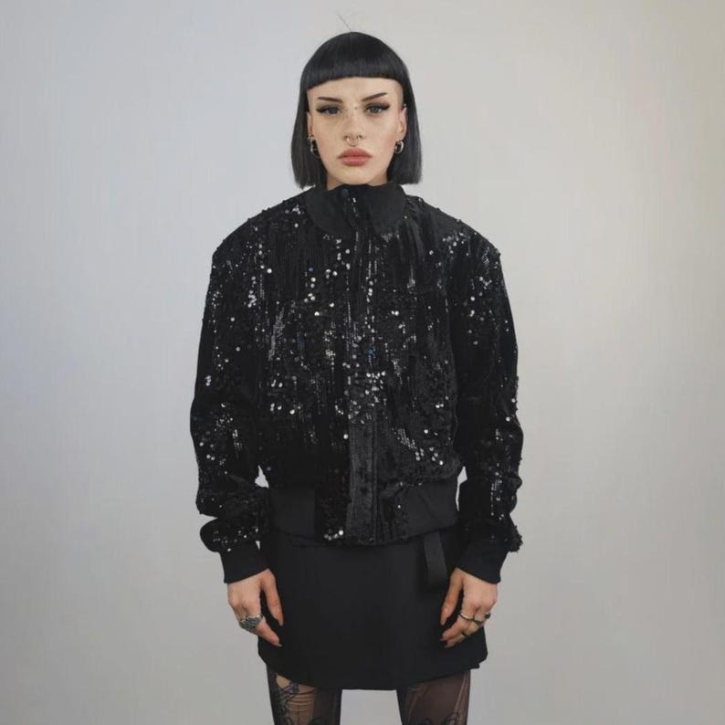This embellished varsity jacket is the definition of dark glamour. The gloss glitter sequins create an unforgettable shiny effect. Styled as an oversized cropped blazer or a short bomber, this unisex embellished piece is ready for the club or a festive gathering. A durable, show-stopping coat for your boldest maximalist ensembles, providing the essential sparkle for any disco look.