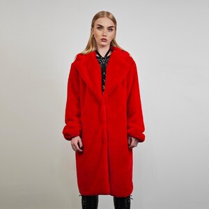 May include: A vibrant red faux fur coat with a wide collar and long sleeves. The coat is knee-length and has a soft, plush texture. The model is wearing black boots. This outerwear is perfect for cold weather.