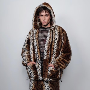 Op de afbeelding: Een set van een jas met capuchon en bijpassende broek met een luipaardprint van imitatiebont. De jas heeft een capuchon met trekkoord en zakken. De outfit is bruin, zwart en crèmekleurig.