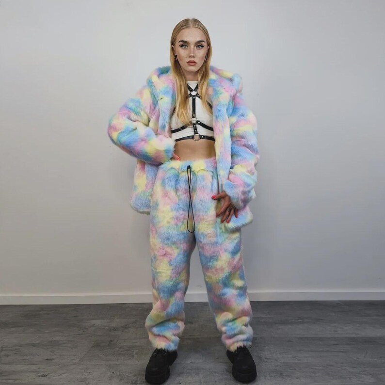 Puede incluir: Un conjunto de chaqueta y pantal&oacute;n de ch&aacute;ndal de piel sint&eacute;tica en colores pastel. La chaqueta tiene capucha y el pantal&oacute;n tiene cord&oacute;n. El conjunto es una mezcla de azul, amarillo, rosa y blanco. La modelo lleva un top corto blanco y zapatos negros.