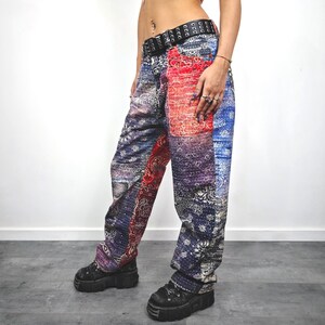 May include: Patchwork pants with a paisley design in shades of blue, red, and purple. The pants have a wide leg and are worn with a black belt and platform shoes. The fabric appears to be a soft material.