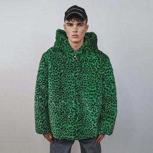 Può includere: Una felpa con cappuccio verde e nera con stampa leopardata e chiusura a zip. La felpa con cappuccio ha un cappuccio ed è realizzata in un materiale morbido e felpato. La persona nell'immagine indossa un berretto da baseball nero.