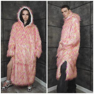 May include: A long, hooded coat made of pink, yellow, and white faux fur. The coat has a relaxed fit and a zipper closure on the side. The hood is lined with white fabric. The coat is worn by a person in the image.