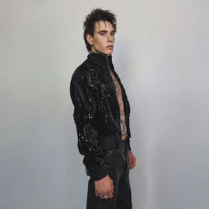 This embellished varsity jacket is the definition of dark glamour. The gloss glitter sequins create an unforgettable shiny effect. Styled as an oversized cropped blazer or a short bomber, this unisex embellished piece is ready for the club or a festive gathering. A durable, show-stopping coat for your boldest maximalist ensembles, providing the essential sparkle for any disco look.