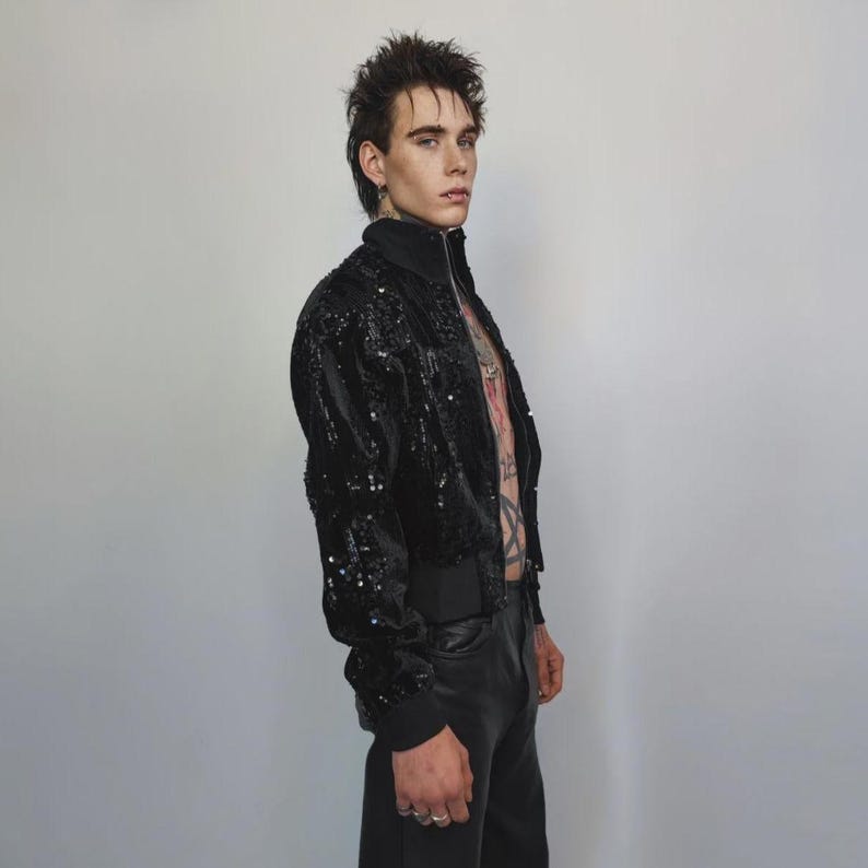 This embellished varsity jacket is the definition of dark glamour. The gloss glitter sequins create an unforgettable shiny effect. Styled as an oversized cropped blazer or a short bomber, this unisex embellished piece is ready for the club or a festive gathering. A durable, show-stopping coat for your boldest maximalist ensembles, providing the essential sparkle for any disco look.