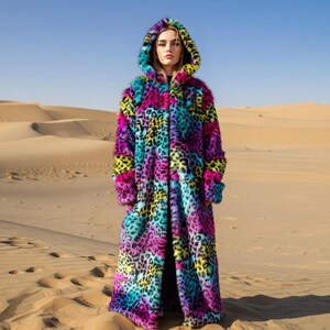 Pode incluir: Um casaco comprido com capuz de pele sintética com estampa de leopardo multicolorida. O casaco apresenta cores como rosa, roxo, amarelo, turquesa e preto. A foto foi tirada no deserto.