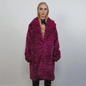 May include: A long, oversized coat with a vibrant pink and black leopard print pattern. The coat has a wide lapel and a relaxed fit, offering a bold fashion statement. The coat is made of a soft, plush material.