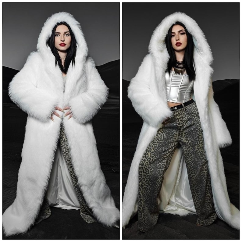 Peut inclure: Un long manteau en fausse fourrure blanche avec une grande capuche. Le manteau est ouvert sur le devant, r&eacute;v&eacute;lant un haut argent&eacute; et un pantalon &agrave; motifs. Le mod&egrave;le pose devant un fond sombre et monochrome.