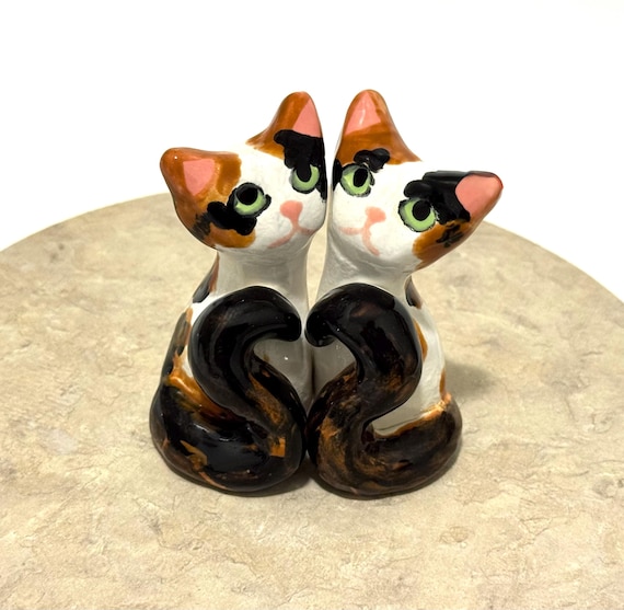 Hand-built ceramic calico cat cake toppers for weddings — tiny sculptural portraits that make the table genuinely personal.