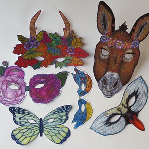 May include: A set of seven colorful paper masks featuring a variety of animal and nature themes. The masks include a butterfly, a donkey, a bird, a flower, and a deer. The masks are all hand-painted and have intricate details.