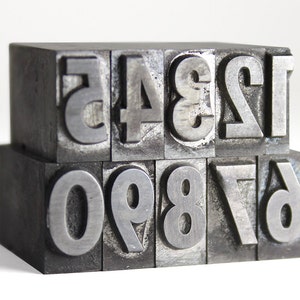 May include: A set of metal printing blocks with the numbers 12345 and 67890 arranged in two rows.