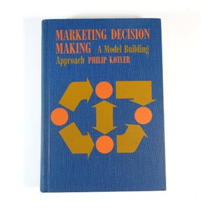 May include: A blue hardcover book with the title "Marketing Decision Making: A Model Building Approach Philip Kotler" in white text. The cover features a stylized graphic of orange circles and gold arrows.
