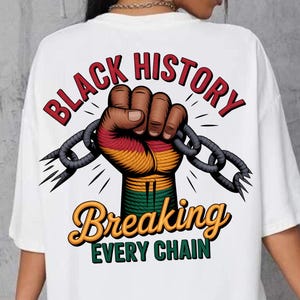 May include: White t-shirt with a graphic design on the back. The design features a clenched fist breaking a chain, with the words "Black History Breaking Every Chain" in red and gold.