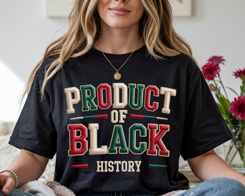 May include: Black t-shirt with the text "PRODUCT OF BLACK HISTORY" in a bold, stitched design. The text features green, red, and cream colours. The shirt is a casual wear item, suitable for everyday use.