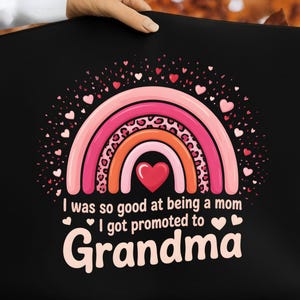 Peut inclure: Sac fourre-tout noir avec un motif arc-en-ciel rose et orange, orné de cœurs et du texte "I was so good at being a mom I got promoted to Grandma". L'arc-en-ciel présente des imprimés léopard.