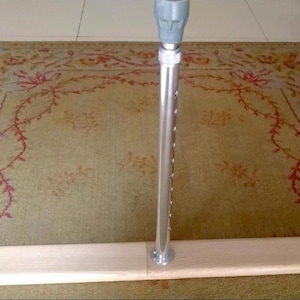 May include: A wooden bar with a metal pole attached to the top. The bar is light brown and the pole is silver.