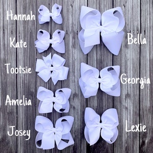 May include: Five white hair bows of varying sizes, labeled with the names Hannah, Kate, Tootsie, Amelia, and Josey.  The bows are arranged in a vertical column from largest to smallest.  On the right side of the image, four larger white hair bows are labeled Bella, Georgia, and Lexie.