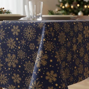 Könnte beinhalten: Eine marineblaue Tischdecke mit einem sich wiederholenden Muster aus goldenen Schneeflocken und kleinen Sternen. Der Stoff hängt über die Kanten eines rechteckigen Tisches und zeigt einen gleichmäßigen Druck verschiedener Schneeflockenmotive.