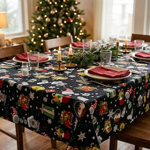 Könnte beinhalten: Eine schwarze, rechteckige Tischdecke mit einem wiederkehrenden Muster aus weihnachtlichen Illustrationen wie Strümpfen, Geschenken, Schneekugeln und weißen Schneeflocken. Der Stoff liegt auf einem mit Tellern gedeckten Esstisch.