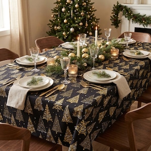 Könnte beinhalten: Eine schwarze Tischdecke mit einem sich wiederholenden Muster aus goldenen Weihnachtsbäumen, gedeckt mit weißen Tellern, goldfarbenem Besteck, klaren Gläsern und beigen Servietten. Ein Mittelstück aus Tannenzweigen, goldenen Kugeln und weißen Kerzen.