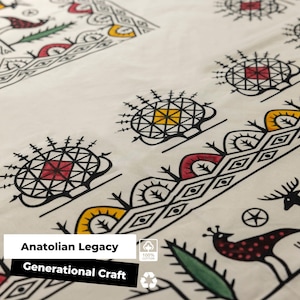 May include: Cream-coloured fabric featuring a repeating pattern of black, red, yellow, and green geometric and animal designs. The text "Anatolian Legacy" and "Generational Craft" is displayed on the bottom left.