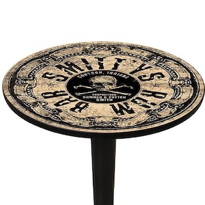 May include: A round bar table with a black base and a distressed, vintage-style top. The top features the text "Smith's Rum Bar" with a skull and crossbones emblem, and the text "Corydon, Indiana".