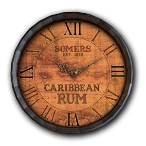 May include: Round wooden wall clock with a dark brown barrel-style frame. The clock face features a map design with the words "SOMERS EST. 1978" and "CARIBBEAN RUM" in a vintage font. Roman numerals mark the hours.