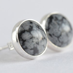 May include: A pair of silver stud earrings with round black and white snowflake obsidian stones.