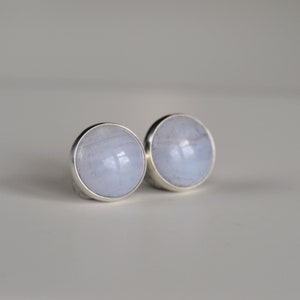 May include: A pair of silver stud earrings with light blue agate stones.