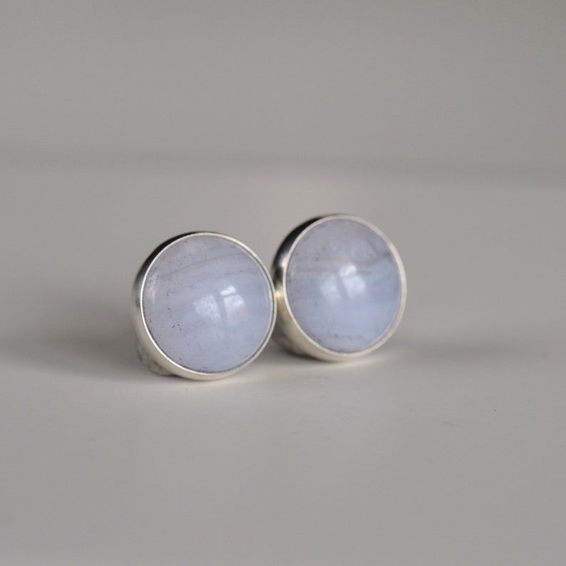 May include: A pair of silver stud earrings with light blue agate stones.