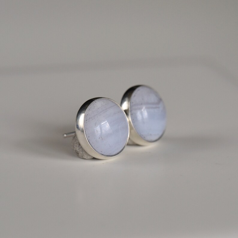May include: A pair of silver stud earrings with blue agate stones.
