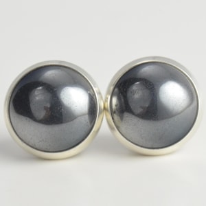 May include: A pair of silver earrings with round, black hematite stones.