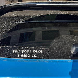 Peut inclure: Une voiture bleue avec un autocollant sur la lunette arri&egrave;re qui dit "tell your bike I said hi".