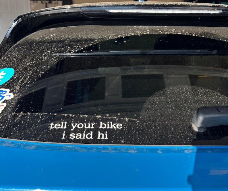 Peut inclure: Une voiture bleue avec un autocollant sur la lunette arri&egrave;re qui dit "tell your bike I said hi".