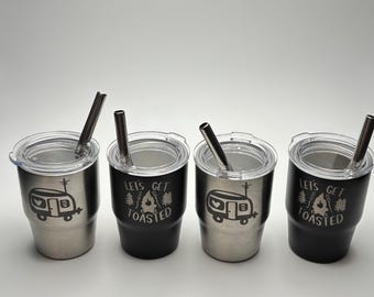 May include: Four stainless steel tumblers with lids and straws. Each tumbler features a black and white design with a camper and the text "Let's Get Toasted".