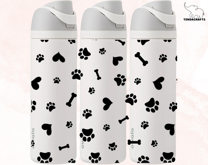 May include: Three white water bottles with black paw prints, hearts, and bone designs. The bottles have a gray lid and a white label with the word "ovala" on it.