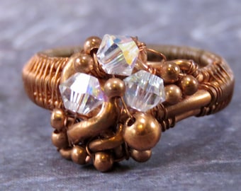 May include: A copper wire wrapped ring with clear iridescent crystals and copper beads.