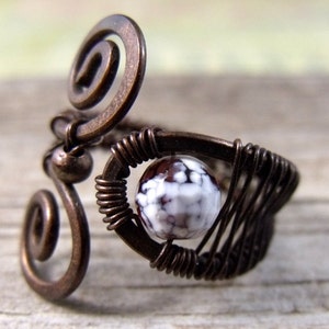 Op de afbeelding: Een ring van koperdraad met een witte en bruine agaat steen. De ring is gemaakt van draad dat gedraaid en om de steen gewikkeld is.