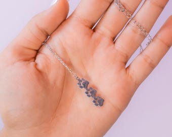 May include: A silver necklace with a pendant of four paw prints.