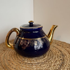 May include: A white ceramic mug with a black handle and the text "But First, Coffee" in a black, bold font. The mug is on a white surface. The mug is approximately 4 inches tall.